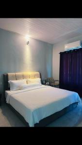 a bedroom with a large bed with white sheets and pillows at Rainbow River View in Jerantut