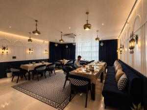 a man sitting at a restaurant with tables and chairs at Hotel Sunshine in Surajpur Jikkla