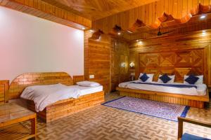 a bedroom with two beds in a room with wooden walls at The Royal Pinewood in Kasol