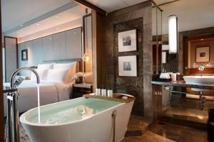 a hotel room with a tub and a bed at Conrad Bangkok in Bangkok