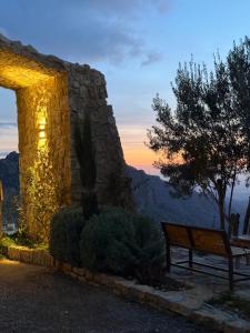 a bench sitting next to a stone wall with a sunset at Dana panorama-green camp in Dana
