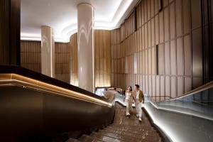 two people walking down an escalator in a building at Conrad Bangkok in Bangkok
