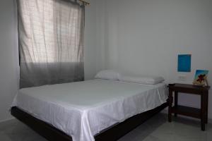 a bedroom with a white bed and a window at San Cristóbal Surf House lll in Puerto Baquerizo Moreno