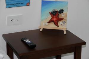 a remote control sitting on top of a table with a painting at San Cristóbal Surf House lll in Puerto Baquerizo Moreno