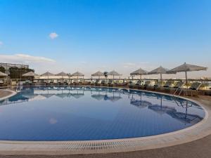 a large swimming pool with umbrellas on top of it at Ibis Abu Dhabi Gate in Abu Dhabi