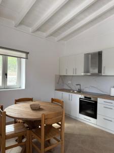 a white kitchen with a wooden table and chairs at Almyra Suites in Khalíkia