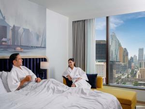 a man and woman sitting in bed in a hotel room at Novotel Bangkok Platinum Pratunam in Bangkok +96 photos