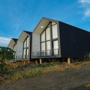 a house with a black and white exterior at Cabin Athenea Sikapuk in Kejajar