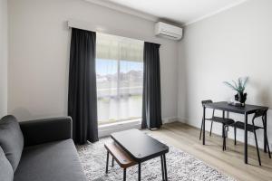 a living room with a couch and a table and a window at Carrum Downs Motel in Carrum Downs