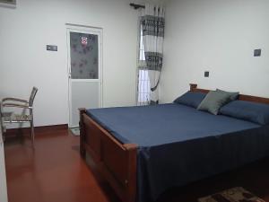 a bedroom with a bed and a chair and a door at Avona Villa in Bopitiya