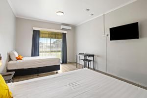 a hotel room with two beds and a flat screen tv at Carrum Downs Motel in Carrum Downs