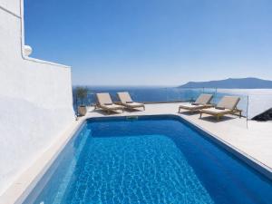 a swimming pool with chairs and a view of the ocean at Diamond on the cliff Hotel&Suites Imerovigli in Imerovigli