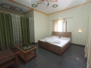 a bedroom with a bed and a table and a window at Hotel Swagat Sarovar in Pauri