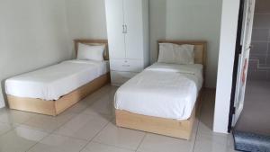 two beds in a small room with white walls at Pusing Classic Semi D House in Pusing
