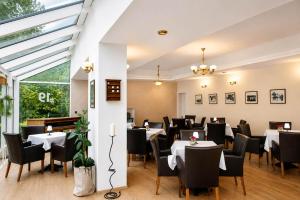 a restaurant with white tables and black chairs at Boutique Hotel at Golf Piestany in Piešťany