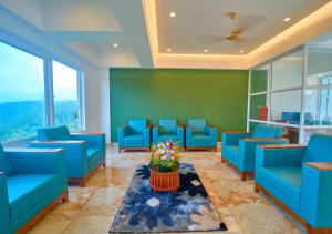 a waiting room with blue chairs and a table with flowers at Nature Green Pool Resort Munnar by VOYE HOMES in Munnar