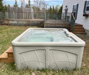 a large hot tub in a yard in front of a house at Spacious Seven Peaks Ridge Quiet Side Hot Tub, Pet Friendly, Fire Pit & Deck in Southwest Harbor