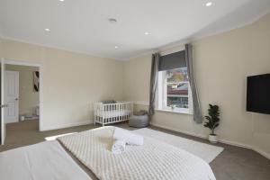 a white bedroom with a bed and a window at Hobart CBD Loft - Walking to CBD in Hobart