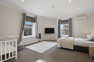 a white bedroom with a bed and a tv at Hobart CBD Loft - Walking to CBD in Hobart