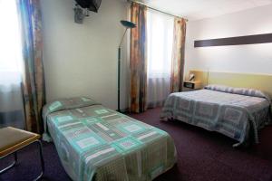 a hotel room with two beds and a window at Le Relais de Fabrègues in Fabrègues