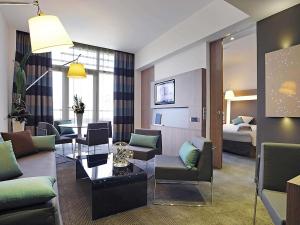 a hotel room with a couch and chairs and a bed at Novotel Avignon Centre in Avignon