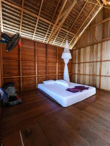 a bedroom with a white bed in a wooden room at Gloria Dive Homestay in Keruo