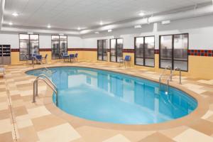a swimming pool in a gym with chairs and tables at Hampton Inn and Suites Alexandria in Alexandria
