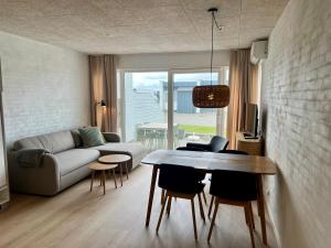 a living room with a couch and a table and chairs at Agger Tange Feriecenter lejligheder - 100 m fra Vesterhavet in Vestervig