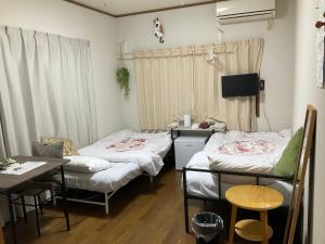 a room with two beds and a desk and a table at Guesthouse Yui in Hongu