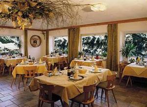 une salle à manger avec des tables et un chiffon de table jaune dans l'établissement Pensione Vittoria, à Colfosco