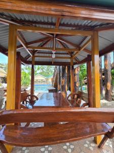 a wooden table and chairs under a pavilion with a table and benches at Gilkrissa Garden in San Nicolas
