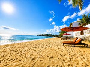 a beach with an umbrella and chairs and the ocean at Dutch Bay Villa - Trincomalee in Trincomalee