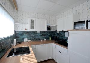 a kitchen with white cabinets and blue tiles at LelleBlue Vendégház in Balatonlelle