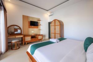 a bedroom with a bed and a desk and a television at Cove Tegeh Bila in Ungasan
