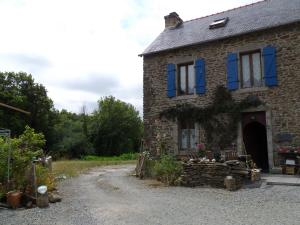 una vieja casa de piedra con persianas azules. en Tyrbourg en Lopérec