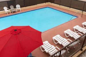 a red umbrella sitting next to a swimming pool at Ramada by Wyndham San Antonio Near SeaWorld - Lackland AFB in San Antonio