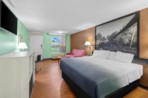 a hotel room with a large bed and a pink chair at Super 8 by Wyndham Gaffney in Gaffney +39 photos