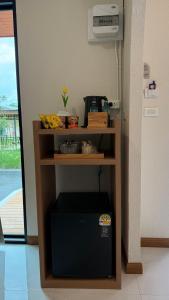 a room with a shelf with a microwave and a television at ภัสรา รีสอร์ท in Ban Nong Khla