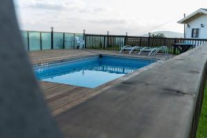 a swimming pool with a wooden deck and chairs at Velen Harmony- בקתות מושלמות עם בריכה במתחם in ‘Ein el Asad