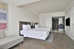 a white bedroom with two beds and a couch at Le Meridien Amritsar in Amritsar