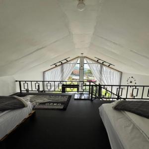 a bedroom with two beds and a large window at Cabin Athenea Sikapuk in Kejajar