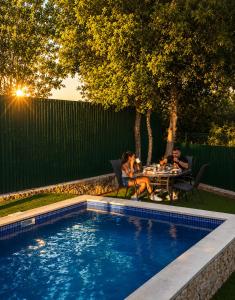 a group of people sitting around a table by a pool at Casa del mir in Dayr al Qamar