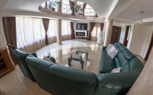 a living room with a green couch and a table at Elegant Private Villa with 3 Bedrooms, Office, and shared courtyard, Perfect for 8 Guests in Piteşti