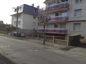 a tree on a sidewalk next to a building at Residence les Goelands in Ouistreham