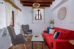 a living room with a red couch and two chairs at Casa Aestas in Lachania