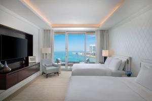 a hotel room with two beds and a flat screen tv at Waldorf Astoria Doha Lusail in Doha
