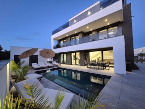 a large house with a swimming pool in front of it at Luxury Villa Vesper- Heated Pool, Hot Tub, Rooftop terrace, Gym in Vodice