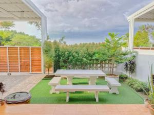 a patio with a table and benches on the grass at ลิบเบล โฮมสเตย์ in Ban Nong Sa