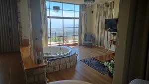 a living room with a tub in a room with a large window at Red and White אדום לבן in Amirim