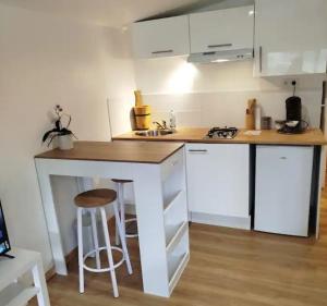 a kitchen with white cabinets and a counter with stools at Le nid douillet in Aydat